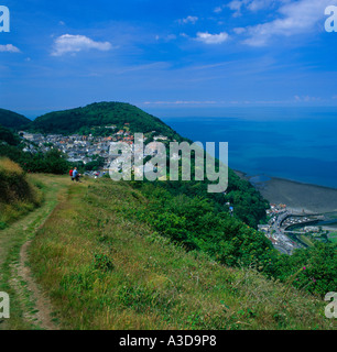 Couple éloigné sur le chemin d'un pavillon d'colline au-dessus de Lynmouth et Lynton et les petits bateaux dans le port nord du Devon en Angleterre Banque D'Images