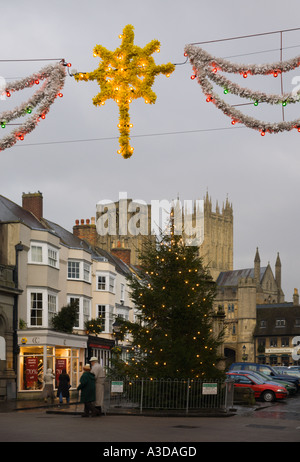 Rue de l'arbre de Noël décorations et Shoppers on un gris nuageux la mi-journée d'hiver avec en arrière-plan La cathédrale de Wells en Angleterre Banque D'Images