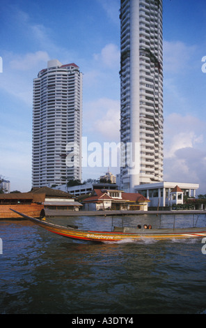 Long boat sur la rivière Chao Phraya avec de grands immeubles en arrière-plan, Bangkok, Thaïlande Banque D'Images