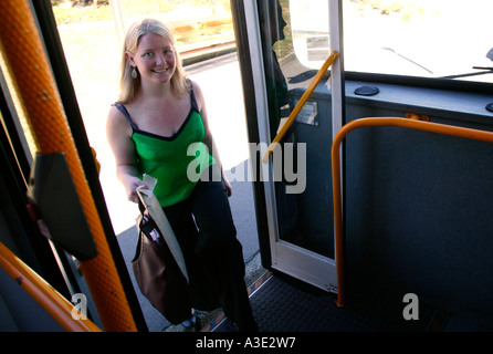 Jeune femme en bus d'embarquement city street, smiling at camera Banque D'Images