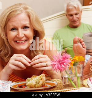 Portrait of a young woman having breakfast in bed avec un homme mûr assis derrière son Banque D'Images