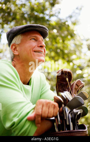 Close-up of a young man leaning on un sac de golf et souriant Banque D'Images