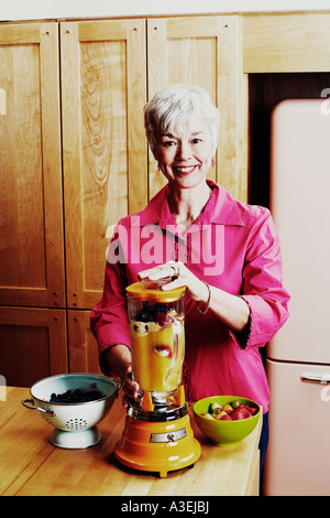 Portrait of a senior woman preparing mango shake dans la cuisine Banque D'Images