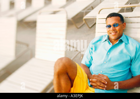 Homme mature couchée sur une chaise de salon Banque D'Images