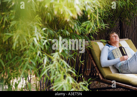 Femme mature de dormir sur une chaise de salon Banque D'Images