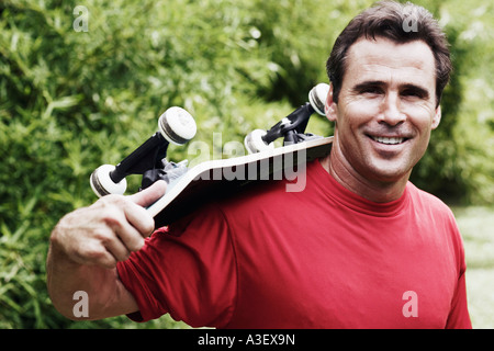 Portrait of a young man carrying a roulettes sur son épaule et souriant Banque D'Images