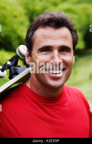 Portrait of a young man carrying a roulettes sur son épaule et souriant Banque D'Images