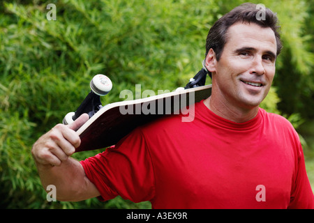 Portrait of a young man carrying a roulettes sur son épaule et souriant Banque D'Images