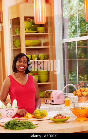 Portrait of a young woman cutting vegetables in the kitchen and smiling Banque D'Images