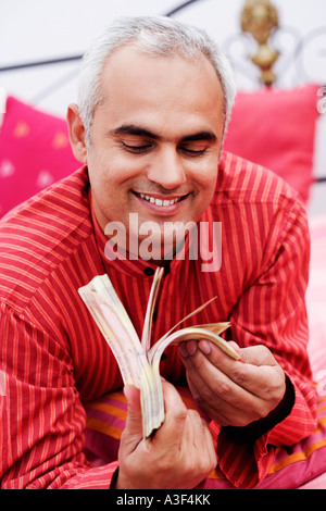 Close-up of a Mid adult man holding devise indienne note and smiling Banque D'Images