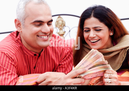 Close-up of a young couple holding devise indienne note and smiling Banque D'Images