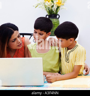 Mid adult woman avec ses deux fils à l'aide d'un ordinateur portable Banque D'Images