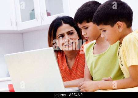 Mid adult woman avec ses deux fils à l'aide d'un ordinateur portable Banque D'Images