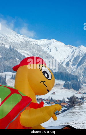 Un ballon gonflé d'être comique au château d'Oex de montgolfières, qui pèse sur le village, les Alpes enneigées en arrière-plan Banque D'Images