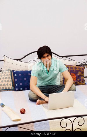 Portrait d'un jeune homme à l'aide d'un ordinateur portable sur le lit Banque D'Images