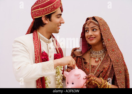 Bride holding a piggy bank avec un groom mettant l'argent dans il Banque D'Images