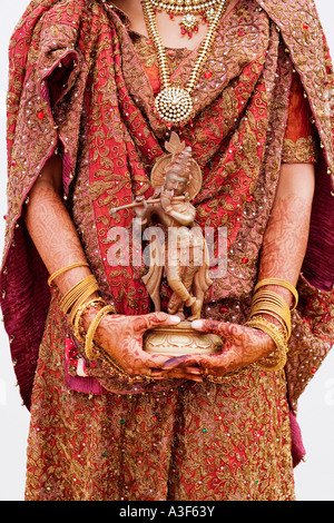 Mid section view of a bride holding une idole du Seigneur Krishna Banque D'Images