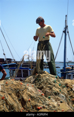 Algarve Portugal, du port de pêche de Faro - un jeune pêcheur réparant ses filets et de tri Banque D'Images