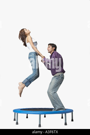 Profil de côté d'un jeune homme et une jeune femme sautant sur un trampoline Banque D'Images