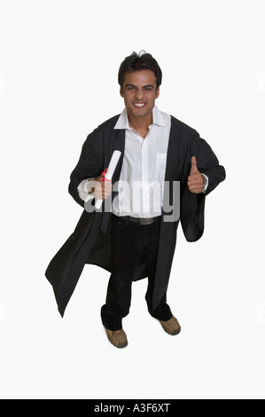 Portrait of a college student holding son diplôme et showing Thumbs up sign Banque D'Images
