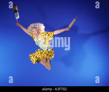 Femme au foyer en sautant en l'air fond bleu Banque D'Images