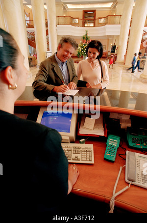 Contrôle de couple à l'hôtel avec réceptionniste en premier plan Banque D'Images