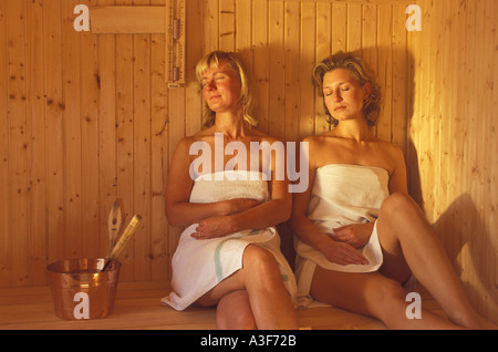 Deux femmes assises à l'intérieur d'un sauna traditionnel en bois en Suède Banque D'Images