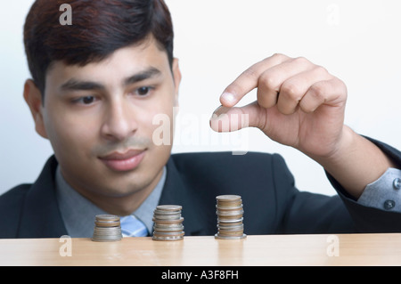 Close-up of a businessman mettre une pièce de monnaie sur une pile de pièces Banque D'Images