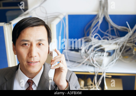 Portrait d'un homme d'affaires à l'aide d'un téléphone dans une salle de serveur Banque D'Images