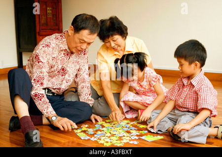 Fille et un garçon jouer puzzle avec leurs grands-parents Banque D'Images