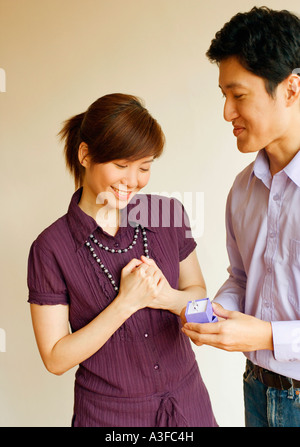 Close-up of a young man smiling et offrant un anneau d'une jeune femme Banque D'Images