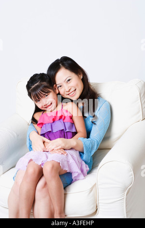 Portrait d'une jeune femme assise dans un fauteuil avec sa fille sur ses genoux Banque D'Images