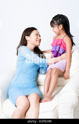 Jeune femme assise dans un fauteuil avec sa fille et smiling Banque D'Images