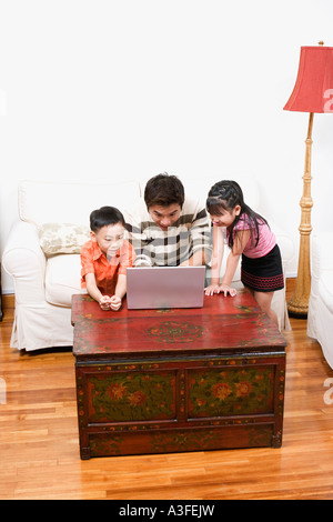 Images à l'aide d'un ordinateur portable avec son fils et sa fille à côté de lui Banque D'Images