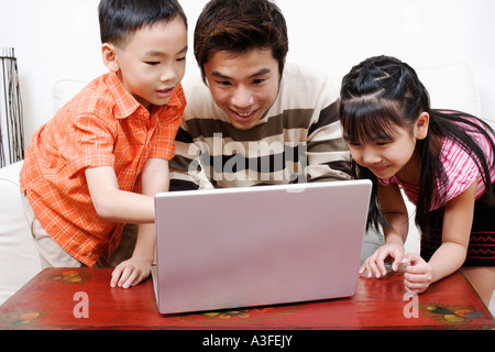 Images à l'aide d'un ordinateur portable avec son fils et sa fille à côté de lui Banque D'Images