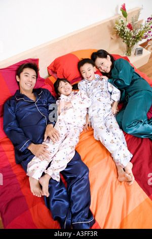 Portrait de deux parents allongé sur le lit avec leurs deux enfants