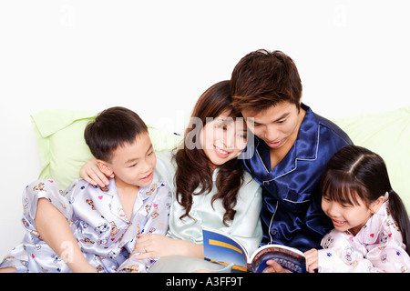 Close-up of a young woman avec leurs enfants la lecture d'un livre sur le lit Banque D'Images