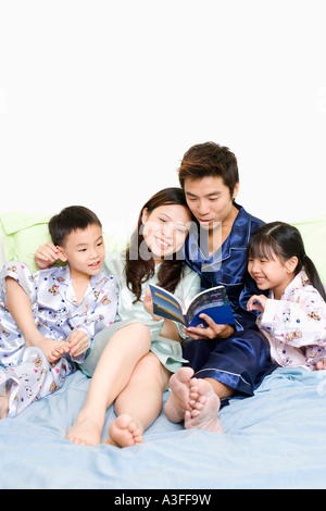 Young Woman Reading a book sur le lit avec leurs enfants Banque D'Images