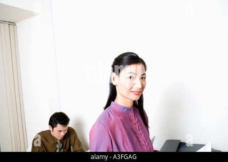 Portrait of a businesswoman smiling with a man dans l'arrière-plan Banque D'Images