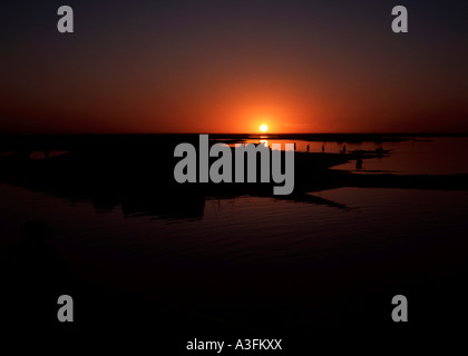 Le soleil se couche derrière un petit bateau, une pinasse, sur le fleuve Niger au Mali Banque D'Images