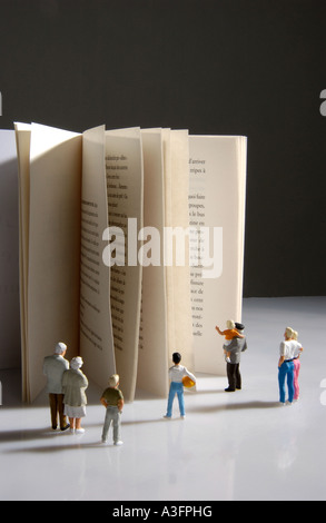 Univers miniatures shaking hands on pile of books Banque D'Images