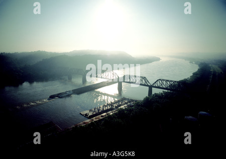 Frais généraux d'une longue balle luminescente barges de transport sous flottante pont de chemin de fer dans la que le soleil jette sur les nuages. Banque D'Images