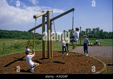 Enfants jouant sur la valse des chevrons en aire de jeux dans le parc de pays avec étage protégé avec l'écorce des arbres Wales UK Banque D'Images