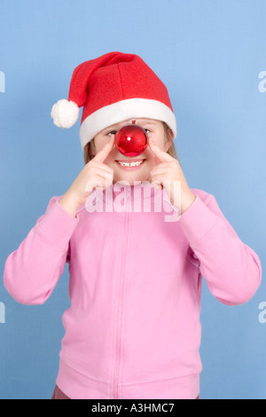Girl in Santa hat holding décoration babiole rouge en face de son nez Banque D'Images