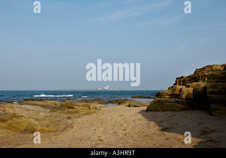 Plage rocheuse déserte à Amble avec phare de l'île Coquet assis à l'horizon, au loin. Northumberland.UK Banque D'Images