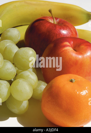 Gros plan de fruits frais bananes raisins pommes Orange dans un bol Banque D'Images