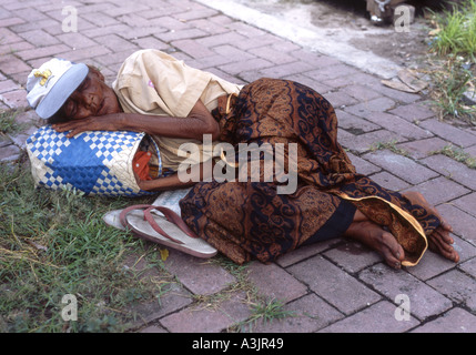 Les personnes âgées femme sans-abri dormant sur le trottoir pendant la journée dans l'Est de Java, Indonésie Madiun Banque D'Images