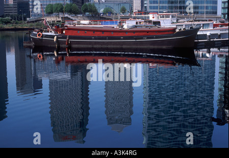 Des réflexions ont eu des tours de bureaux à Canary Wharf, bassin de Blackwall avec péniches amarrées, les Docklands de Londres, Angleterre Banque D'Images