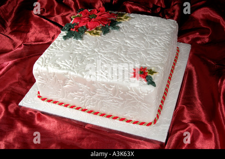 Joliment décorées de Noël gâteau glacé aux fruits avec des feuilles de houx en relief et red poinsettia fleurs faites à partir de la cerise Banque D'Images