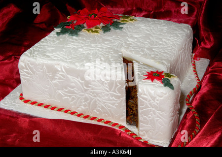 Joliment décorées de Noël gâteau glacé aux fruits avec des feuilles de houx en relief et red poinsettia fleurs faites à partir de la cerise Banque D'Images